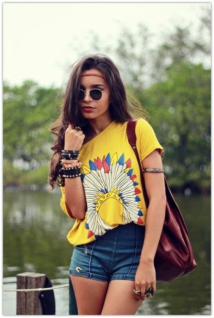 Девушка хиппи в обтягивающих шортах, футболке с принтом и браслетами на руке