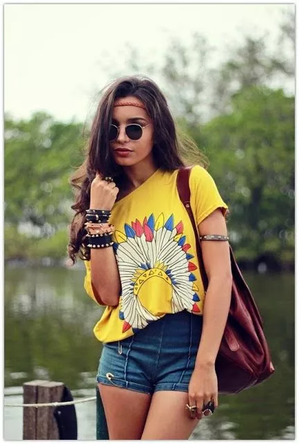 Девушка хиппи в обтягивающих шортах, футболке с принтом и браслетами на руке