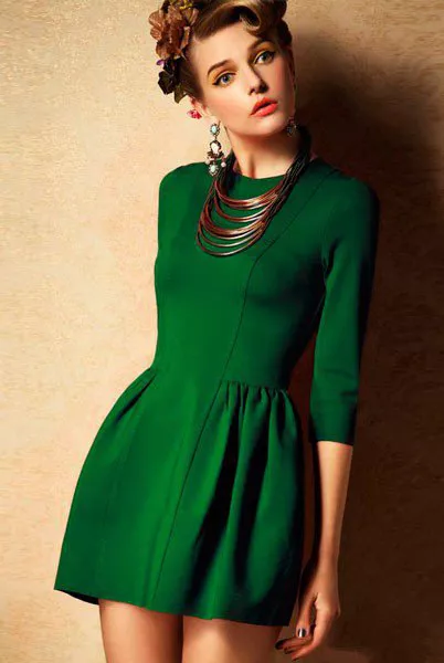 Девушка в коротком зеленом платье с крупным ожерельем на шее и сережками