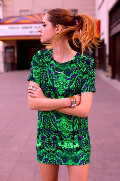 Девушка в коротком, зеленом платье спринтом, браслетом на руке и золотой цепочкой
