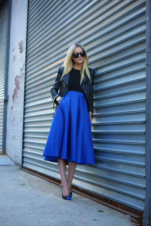 Девушка в синей, расклешенной юбке миди с высокой талией, черной кожаной куртке и просто изумительных туфлях