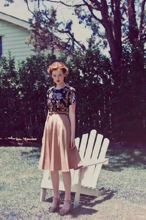 Девушка в юбке, ниже колен, и блузе в цветочек, лук в стиле 70-х