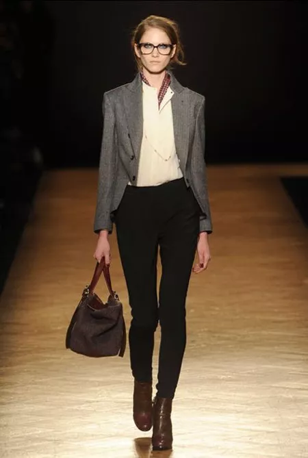 Модель в зауженных черных брюках, белой рубашке, и серый жакет