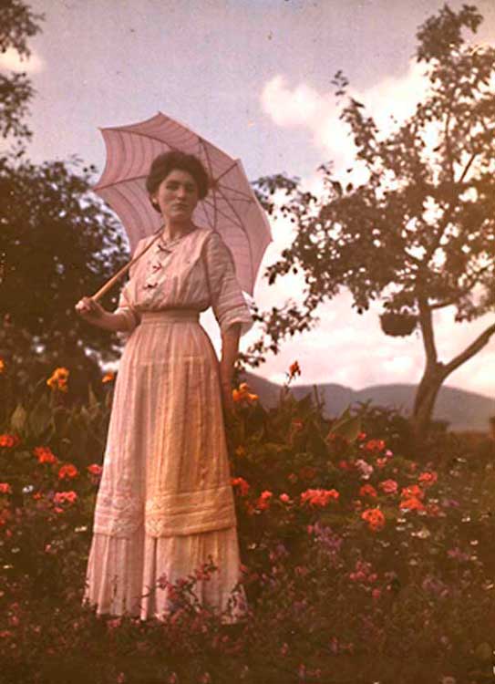 Девушка в длинном платье с зонтиком стоит в саду, 1910 год