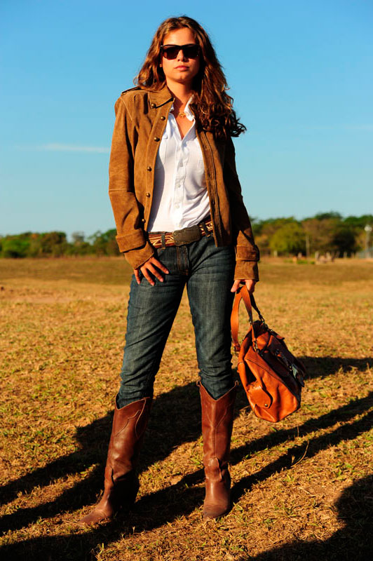 Девушка одета в стиле кантри - джинсы, высокие сапоги и куртка