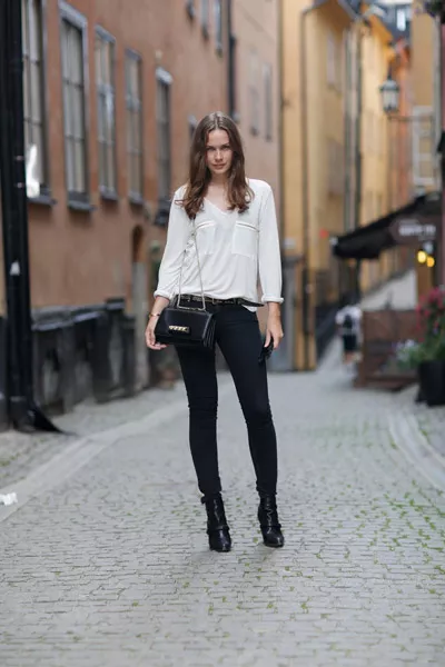 Девушка в черных джинсах и белой блузке