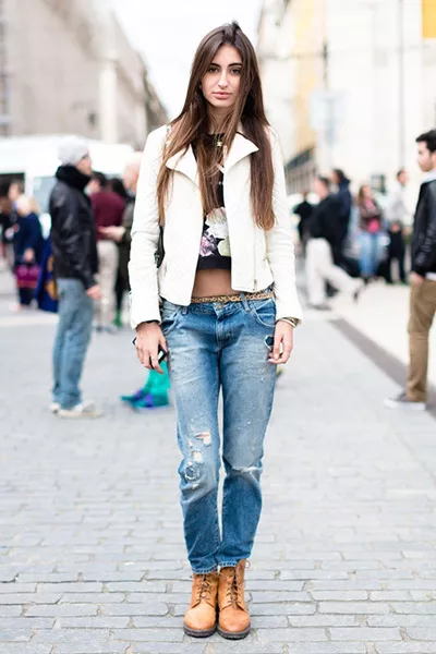 Девушка в коричневых ботинках, слегка рваных джинсах и белой куртке