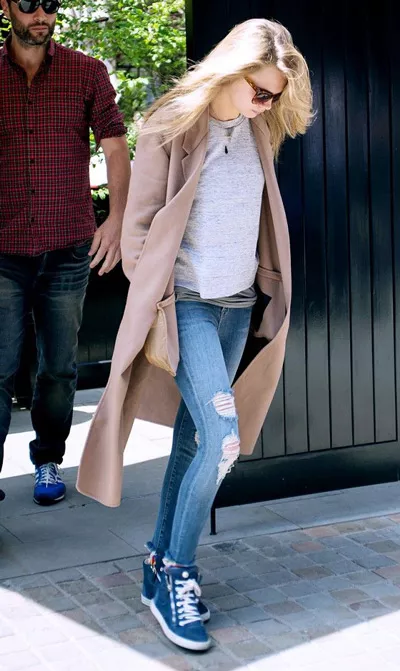 Девушка в рваных джинсах, синих кроссовках и пальто