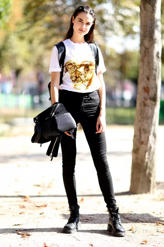 Девушка в черных джинсах с завышенной талией и белой футболке с принтом