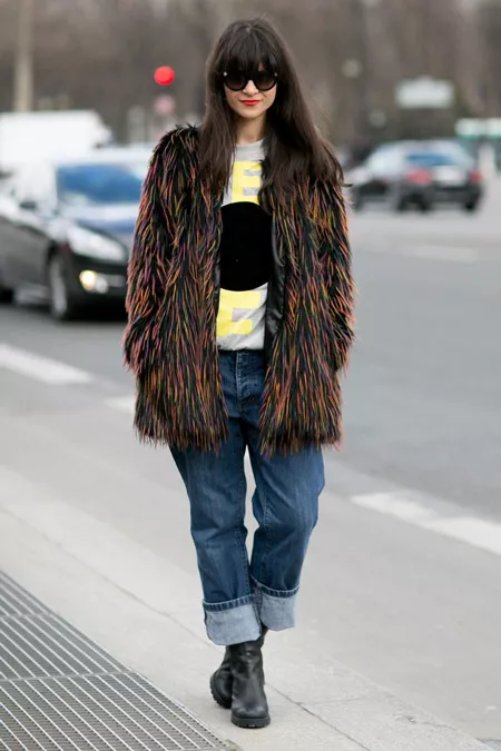 Девушка в широких джинсах и черной меховой шубе с разноцветными ворсинками