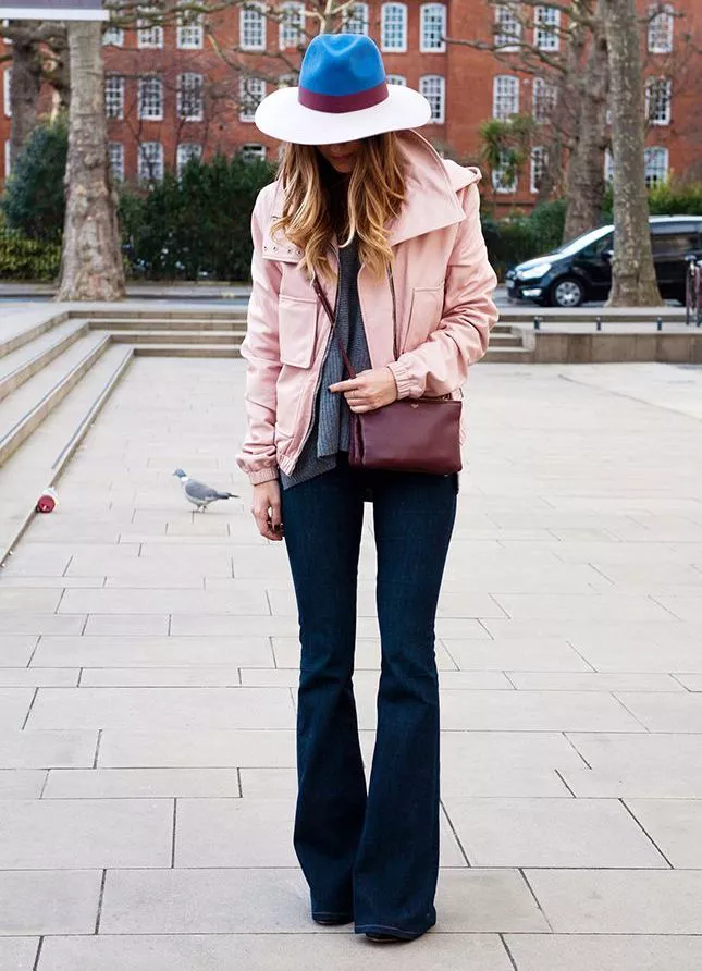 Девушка в розовой куртке, шляпе и джинсах клеш 