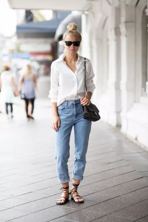 Девушка в джинсах, белой рубашке и сандалиях