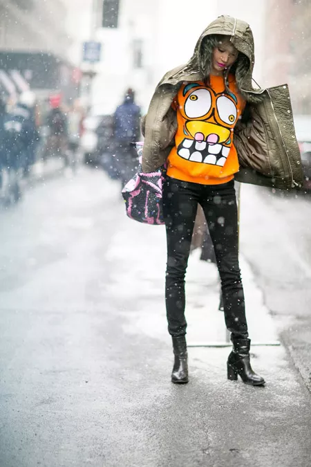 Девушка в черных джинсах, оранжевый свиншот с принтом и куртка с капюшоном