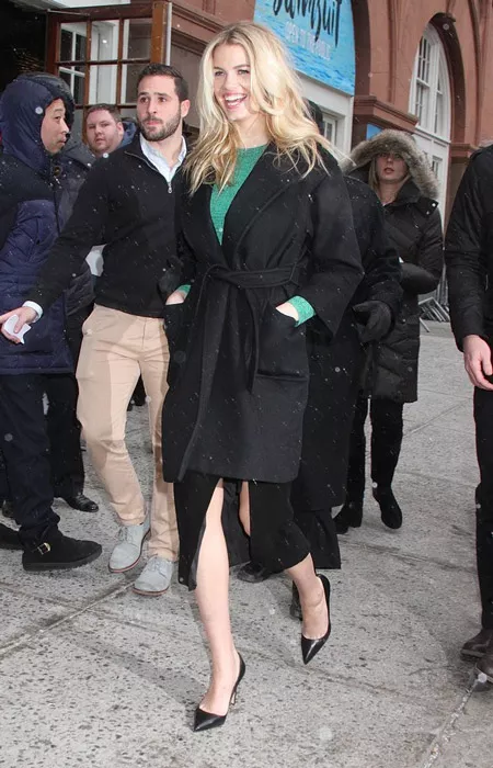 Hailey Clauson в черной юбке с разрезом, зеленая кофточка и черное пальто с поясом