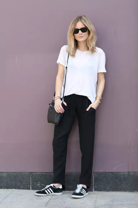 Модель в черных брюках, белая футболка и кеды