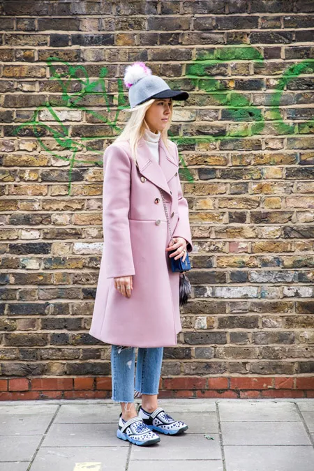 Модель в укороченных джинсах, светло розовое пальто и кепка с помпоном, неделя моды - Лондон осень/зима 2016-2017