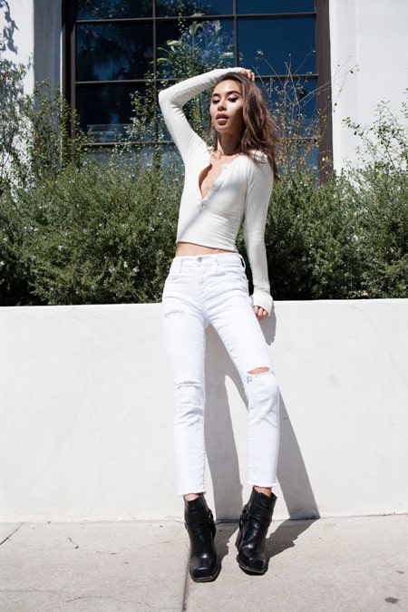 Модель в белых рваных джинсах и кофточка, черные ботинки