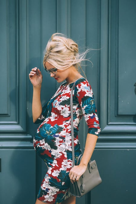 Беременная девушка в обтягивающем платье с ярким цветочным принтом