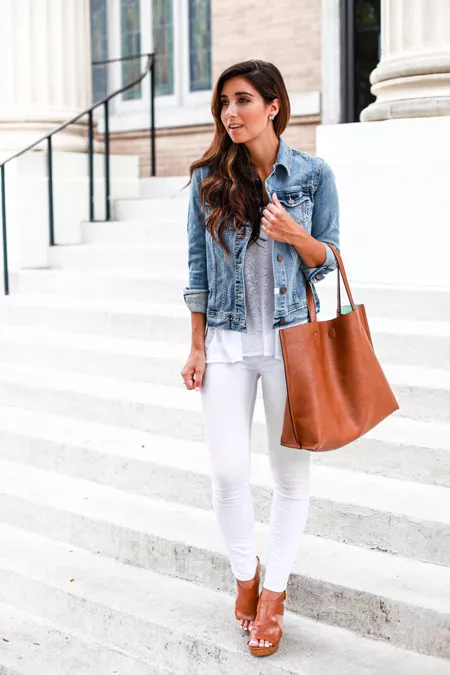 Девушка в в белых джинсах, синей джинсовке и с коричневой сумкой тоут