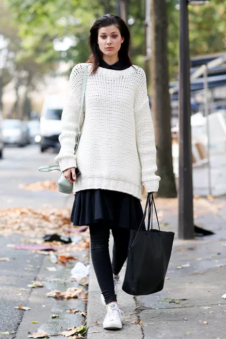 Модель в юбке, белый длиный свитер и черная сумка тоут