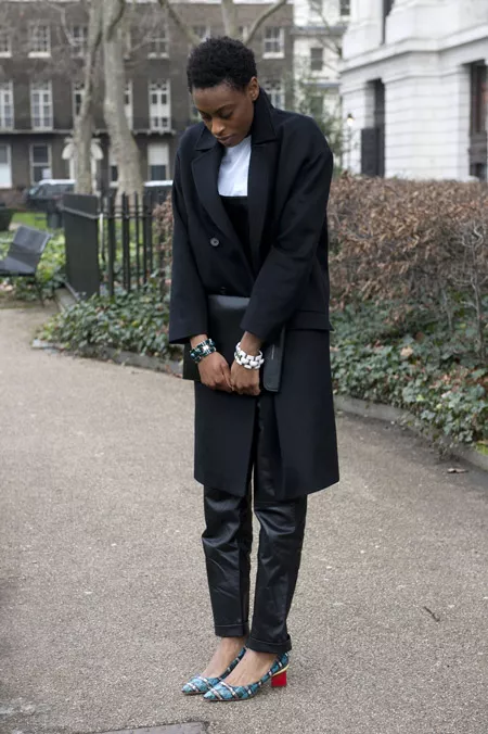 Девушка в черных брюках и пальто чуть выше колена
