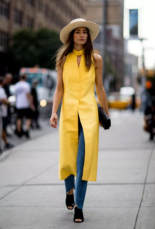 Девушка в желтом длинном жилете, джинсах, черные сабо и шляпа - уличная мода Нью-Йорка весна/лето 2017