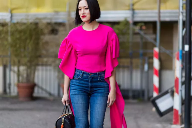 Девушка в джинсах и блузке цвета фуксии