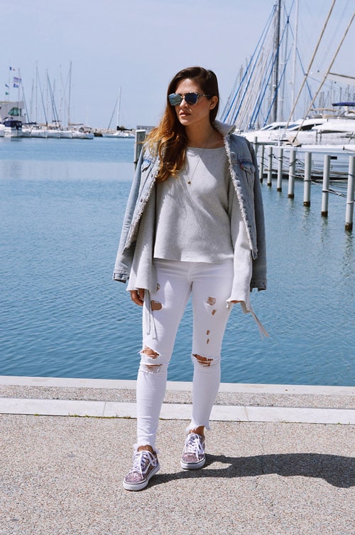 Девушка в белых рваных джинсах, джемпер и джинсовая куртка, кеды