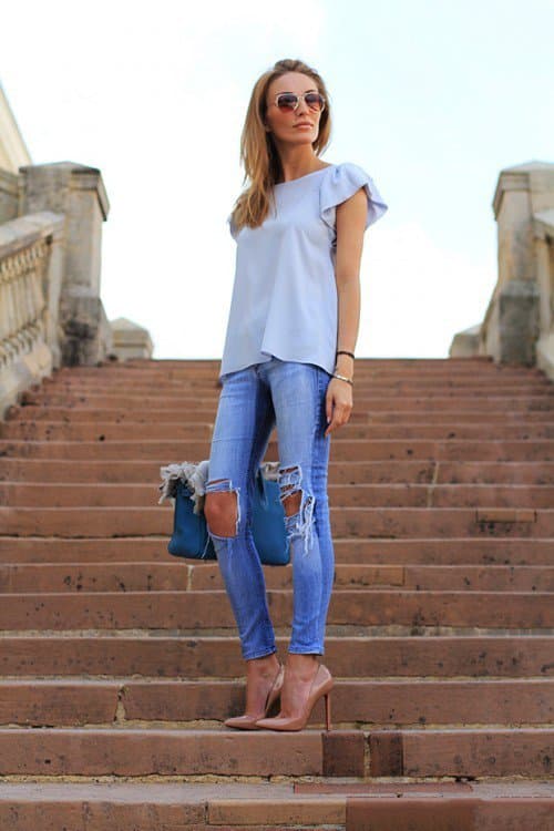 Девушка в рваных джинсах, голубая блузка и бежевые туфли лодочки