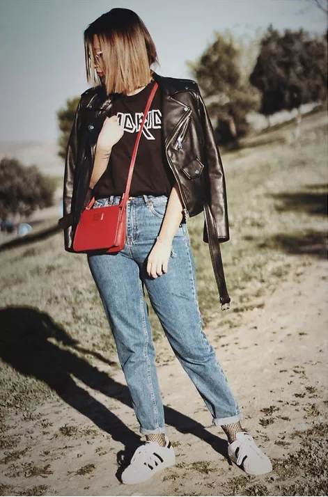 Модель в джинсах американках и куртка косуха и красная сумочка