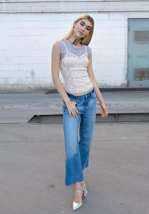 Девушка в укороченных джинсах, светлый топ и серебристые босоножки