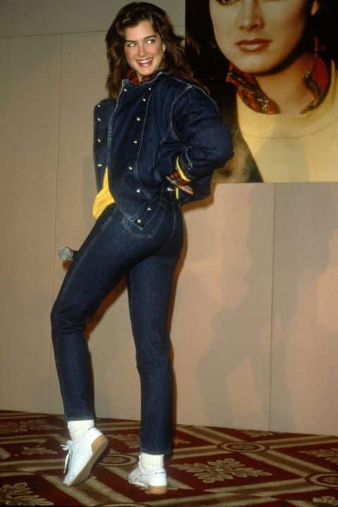 Брук Шилдс в темно-синих джинсах и куртке, белые кеды