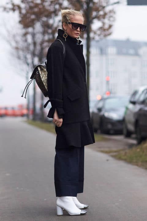 Девушка в черном пальто, темно-синих брюках и белых ботильонах