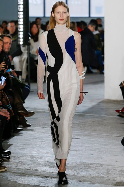 Модель в белом платье с черно синими вставками ниже колен от Proenza Schouler