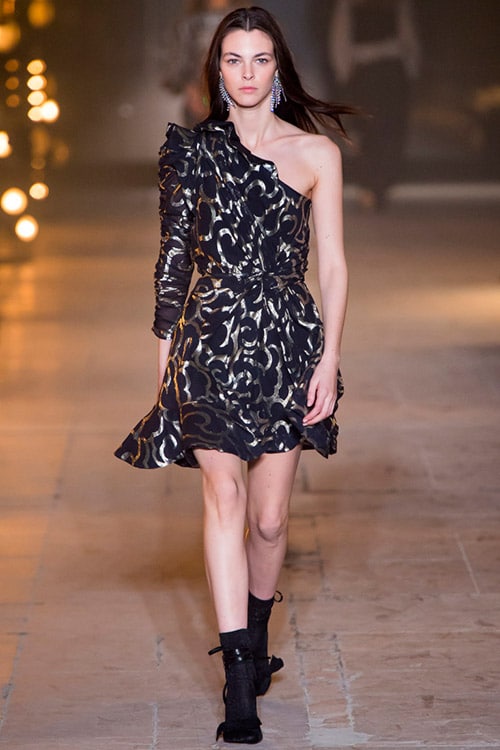 Модель в черном платье с золотыми узорами на одно плечо от Isabel Marant
