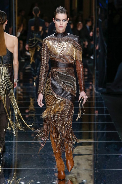Модель в коричневом платье с кожаными вставками ниже колен от Balmain