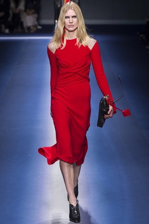Модель в красном платье ниже колен с вырезами на плечах от Versace