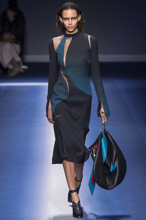 Модель в темном платье асимметричного покроя ниже колен от Versace