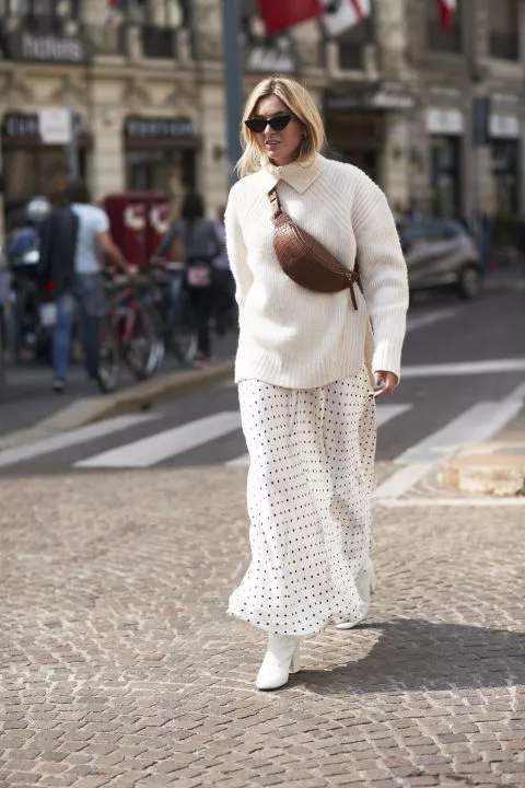 Девушка в белой юбке макси и вязанном свитере оверсайз