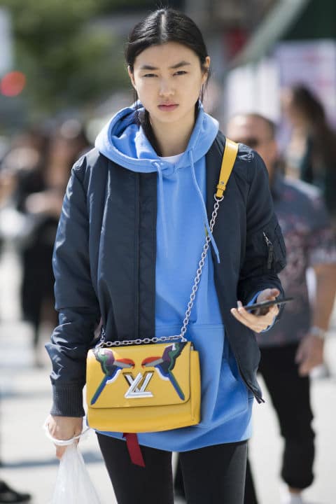 Девушка в голубой толстовке и синей куртке, желтая сумка