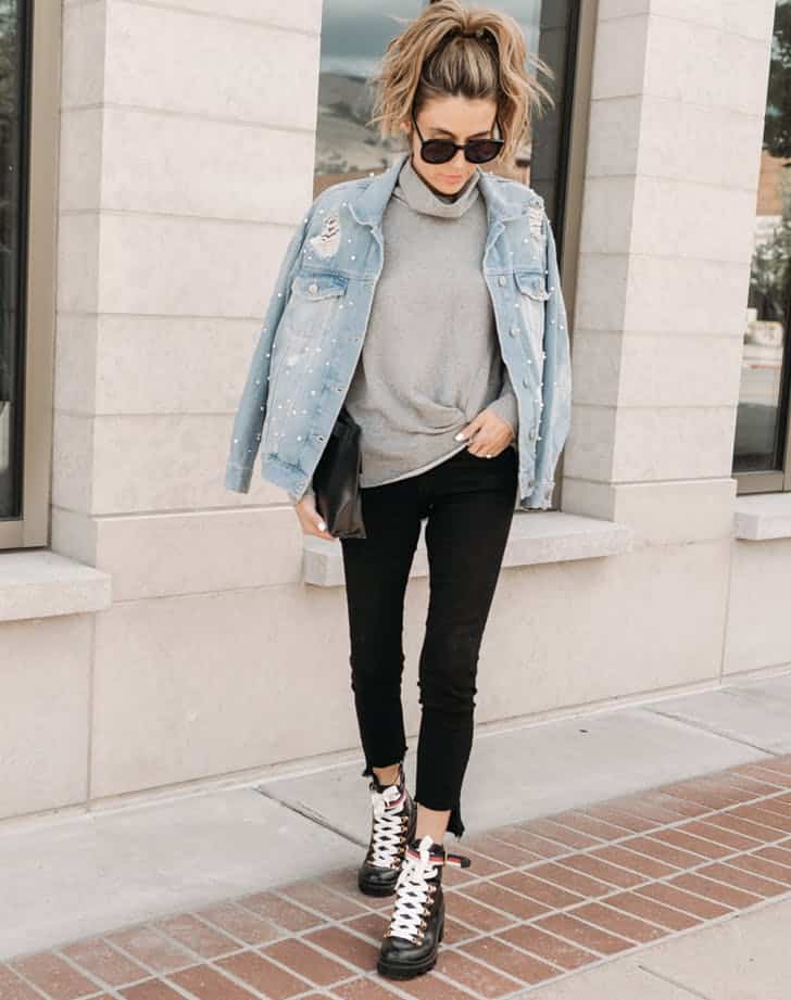 Девушка в черных джинсх скинни, серый свитер и джинсовая куртка