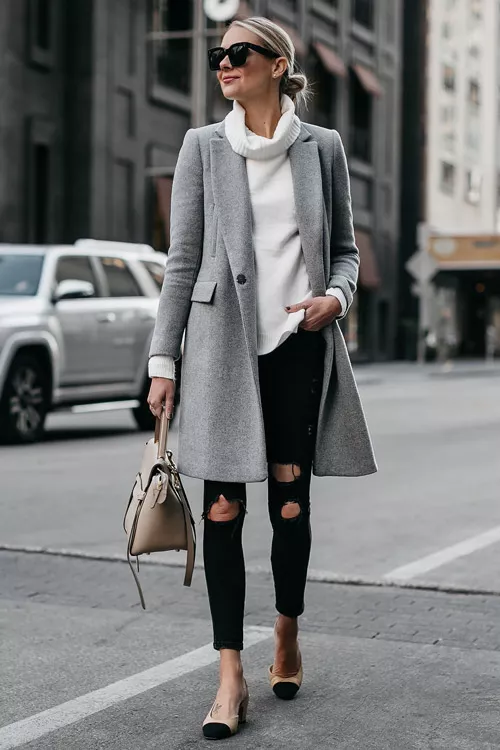Девушка в черных джинсах, белом свитере и сером пальто