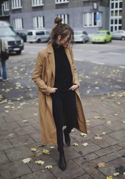 Девушка в черных джеггинсах, свитере и пальто цвета кемал