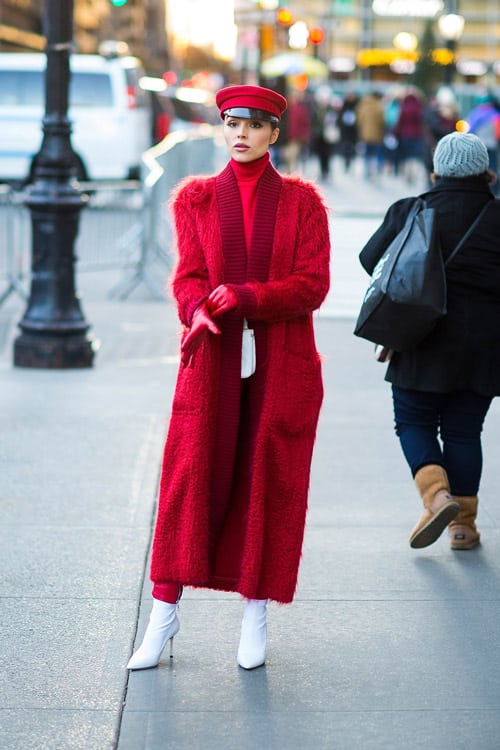 Девушка в длинном красном пальто, кепке и белых ботильонах