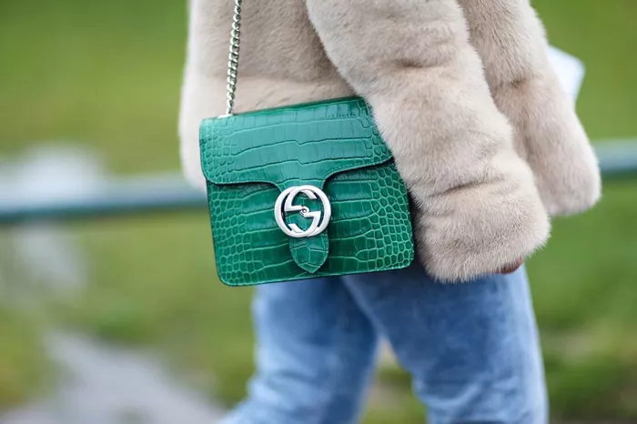 Девушка в джинсах, шубка и зеленая сумочка