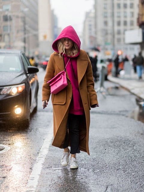 Девушка в коричневом пальто, толстовка с капюшоном цвета фуксии, кеды и розовая сумка