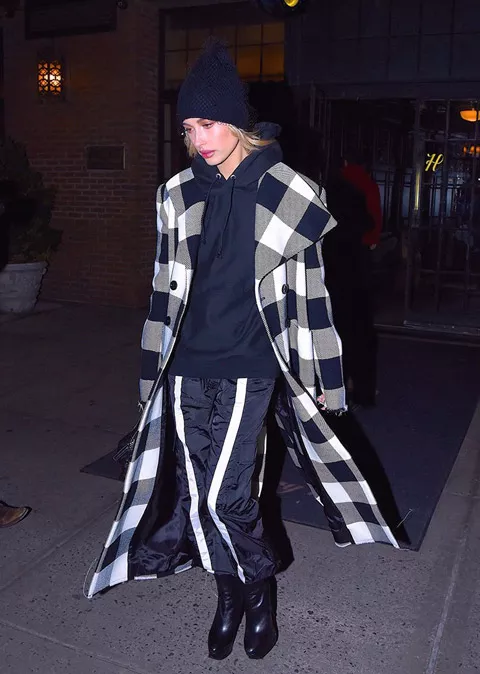 Хейли Болдуин в черных брюках с белыми полосками, толстовк, черно-белое пальто в клетку и шапка