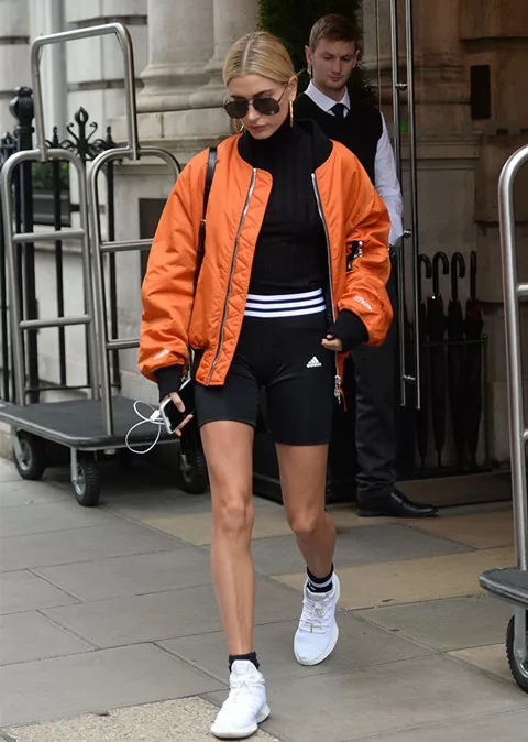 Хейли Болдуин в черных спортивных шортах, водолазка и оранжевый бомрер, елые кроссовки