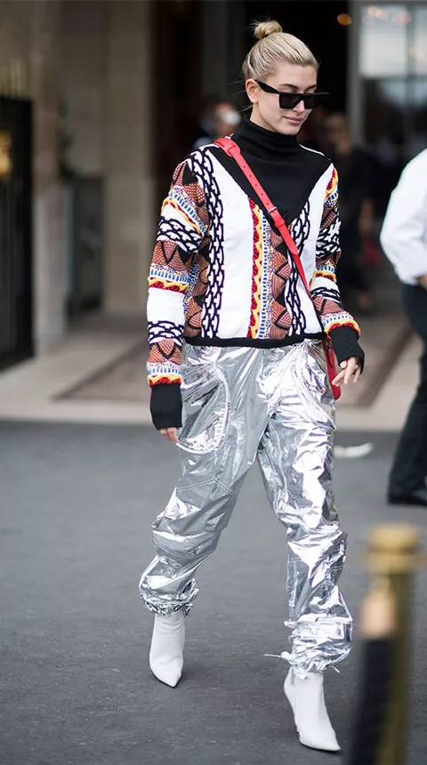 Хейли Болдуин в серебристых штанах, разноцветный свитер и белые ботильоны