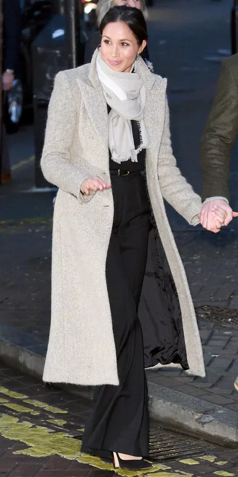 Меган Маркл в сером длинном пальто, расклешенных черных брюках и шарфе
